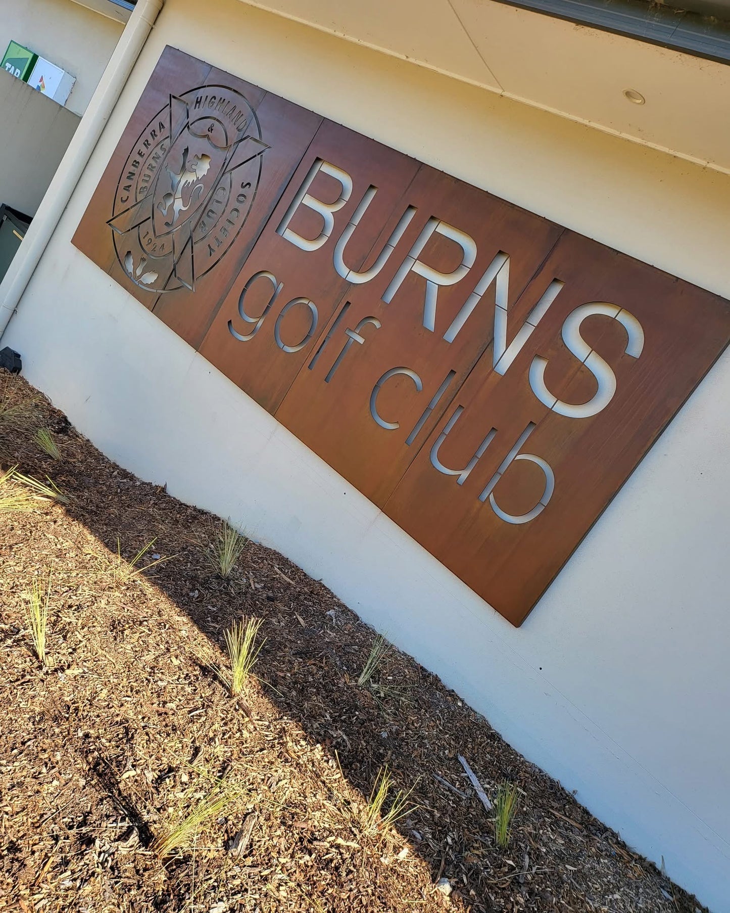Custom-designed corten steel business sign mounted on building facade, featuring laser-cut logo and natural rusted patina for a distinctive, modern look.