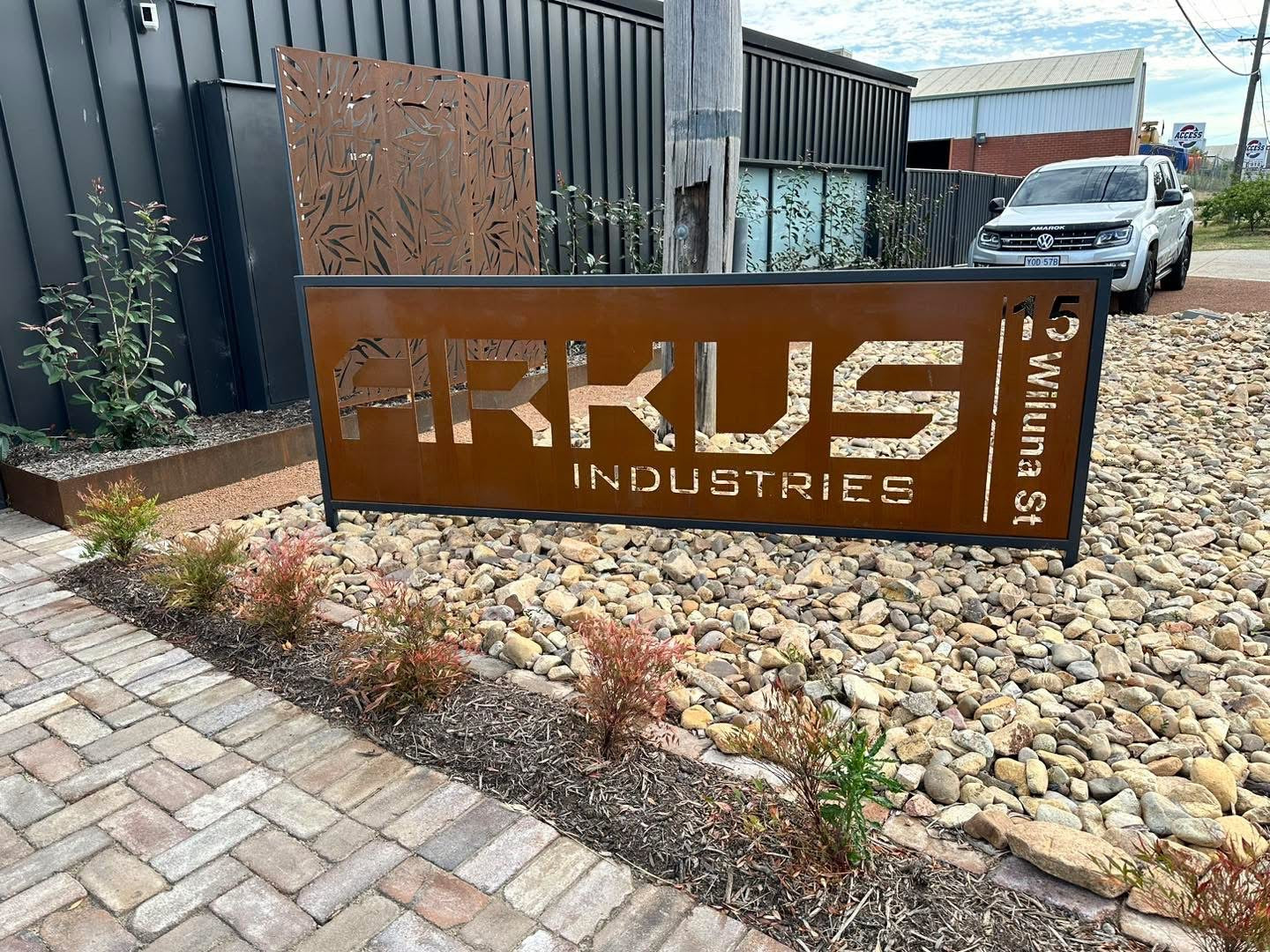 Corten steel business sign with precision laser-cut lettering, featuring a rusted patina finish for a modern, industrial look.