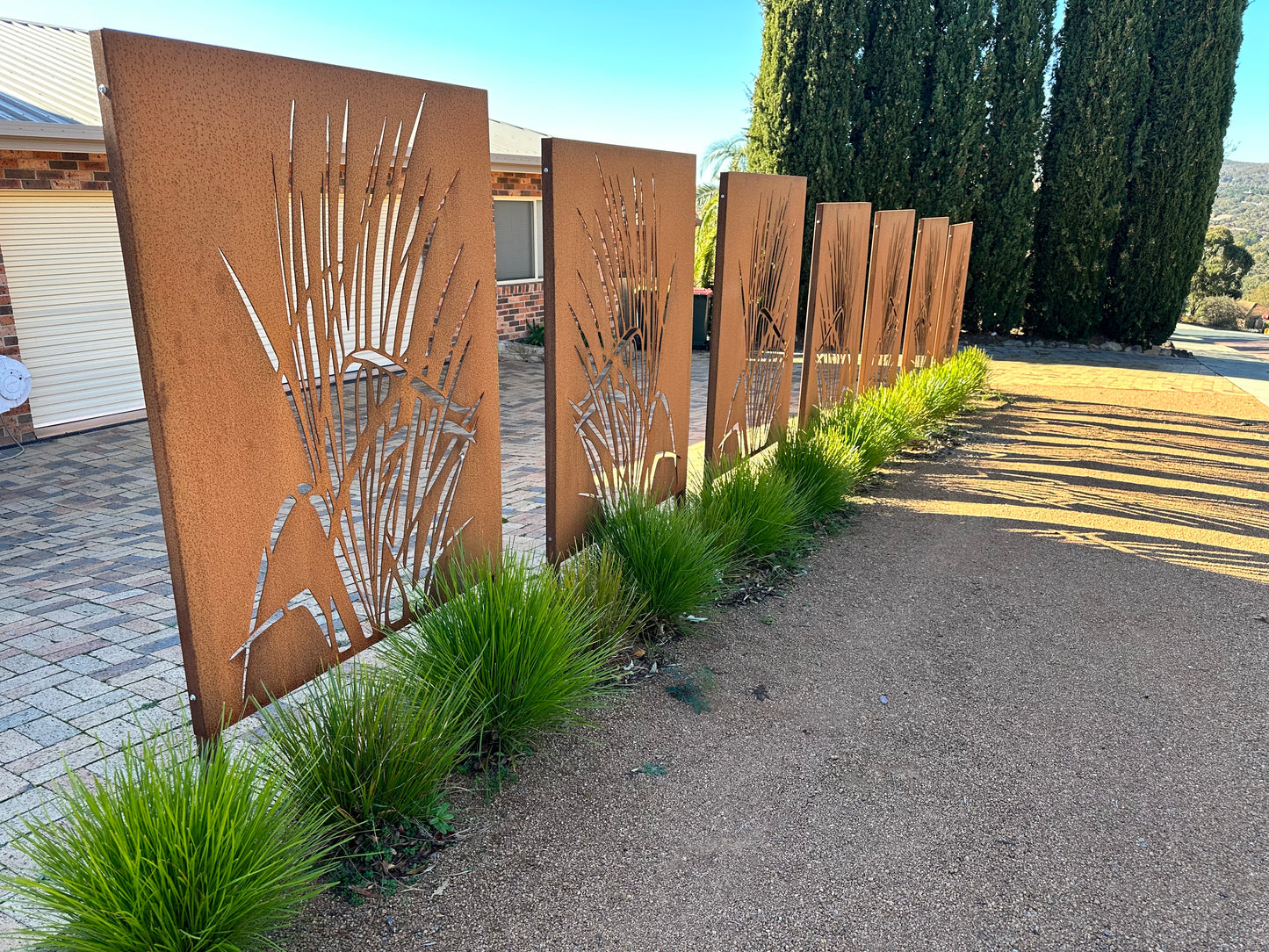 even corten steel privacy panels with laser-cut decorative designs, spanning the front of a house to create privacy, modern street appeal, and an architectural focal point.